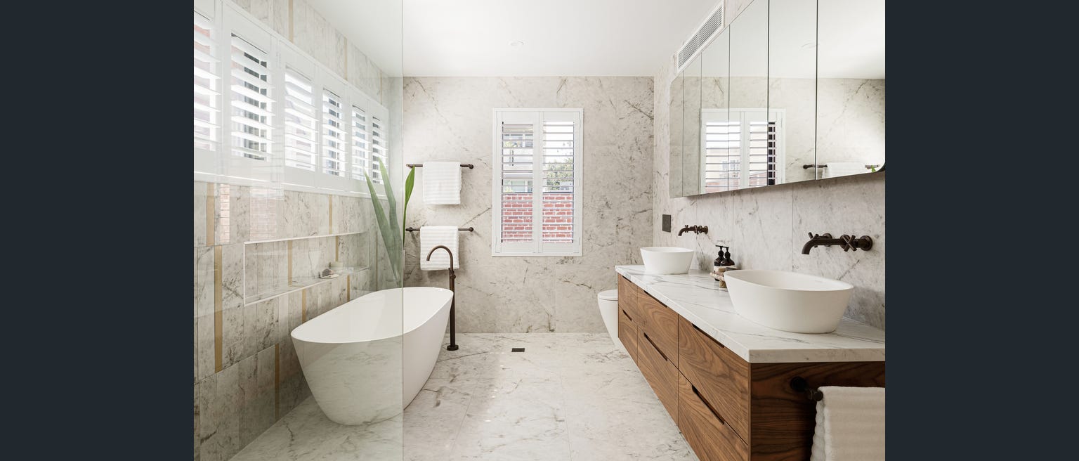 Marble bathroom with freestanding bath and twin vessel basins after plumbing rough-in and fit-off